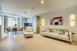 Un salon moderne avec un canapé, une table à manger et des chaises, une cuisine en arrière-plan et un grand tableau abstrait accroché au mur.