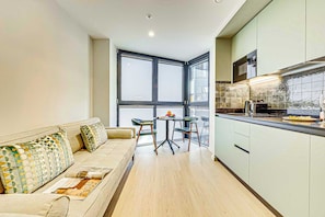 Un apartamento moderno con sofá, mesa de comedor, sillas y zona de cocina.
