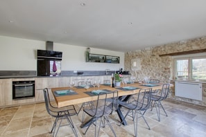 Une cuisine spacieuse dotée d’un grand îlot central, d’appareils électroménagers modernes et d’un mur d’accent en pierre.
