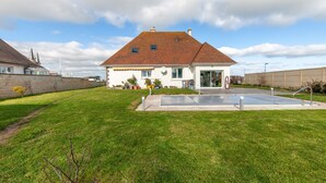 Ein Haus mit großem Rasen, Swimmingpool und Garage.