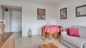 A living room with a dining table, sofa, and a large mirror. - Swingcat - Charmant appt pour 2 (Athis Mons)