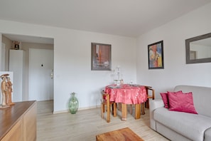 Una sala de estar con una mesa de comedor, sofá y un espejo grande.
