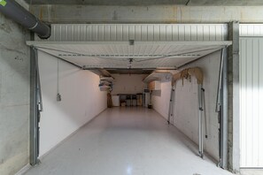 A clean, empty hallway with a white ceiling, concrete walls, and a closed garage door. - Côté Port - Appt sortie privée vers le port (Arcachon)