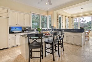 A spacious kitchen with a large island, white cabinetry, and a view of the outdoors.