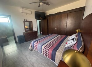 A bedroom with a bed, a dresser, a television, and a ceiling fan.