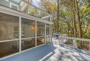 A modern house with a large deck, outdoor seating, and a grill area.