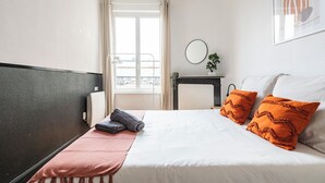 Une chambre d’hôtel avec un lit, une table de chevet avec un miroir, une fenêtre avec des rideaux et une vue sur l’extérieur.