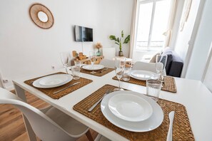 Una mesa de comedor dispuesta con platos blancos, vasos transparentes y cubiertos, rodeada de individuales tejidos.