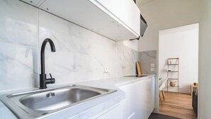 Une cuisine moderne dotée d’un évier en acier inoxydable, de meubles blancs et d’un plancher en bois.