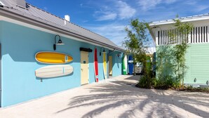 A pathway lined with surfboards on a building's exterior wall, leading to a door. - Margaritaville Townhome Retreat (Kissimmee)