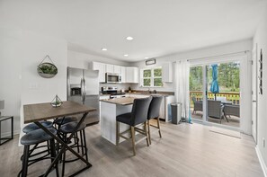 Una cocina moderna con armarios blancos, electrodomésticos de acero inoxidable y una isla central con taburetes de bar.