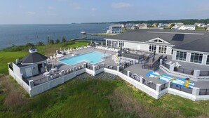 A large house with a swimming pool, a covered patio, and a view of the water.
