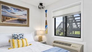 Camera da letto con un letto, un quadro, una finestra con vista, una lampada a parete e un termosifone.