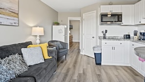 Un apartamento moderno con sala de estar, cocina y un pasillo que lleva a otra habitación.