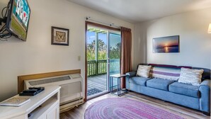 Ein Wohnzimmer mit Sofa, Fernseher, einem gerahmten Bild und Blick durch eine Glastür.