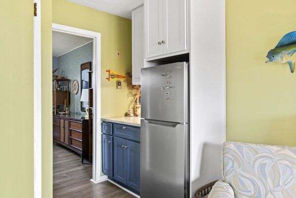 A kitchen with a stainless steel refrigerator, wooden cabinets, and a patterned wall.