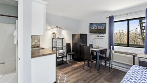 A compact room with a kitchenette, a dining area, and a bed. - Assateague Inn 111 by Seaside Vacations & Sales (Chincoteague Island)