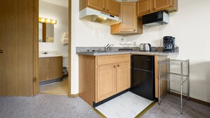 Una cucina compatta con mobili in legno, un forno a microonde integrato, una macchina da caffè e un'lavastoviglie.