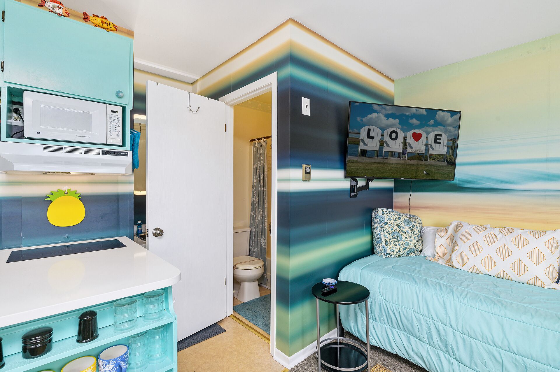 A compact room with a bed, a small table, a microwave, and a toilet.