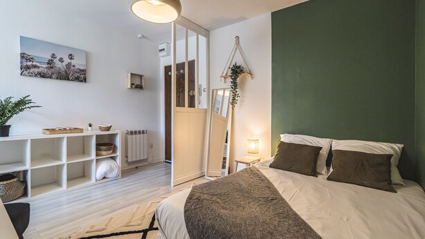 Een slaapkamer met een bed, een bureau en een groene wand.