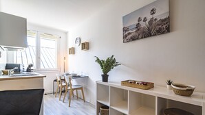 Een keuken met een eethoek, houten stoelen, een potplant en een plank met manden.
