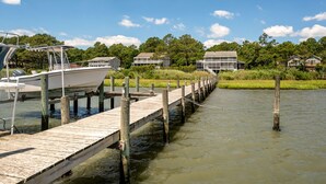 A wooden pier extending into a body of water with a boat docked at the end. - The Happy Crab by Seaside Vacations & Sales (Chincoteague Island)