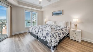 Quarto com cama, abajures, ventoinha no teto, janela com persianas e um quadro na parede.