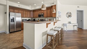 Une cuisine moderne avec des meubles en bois, des appareils électroménagers en acier inoxydable et un îlot central doté de tabourets.