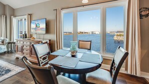 A dining area with a view of the sea, a television on the wall, and a decorative fish on the ceiling. - Sunset Bay 319 by Seaside Vacations & Sales (Chincoteague Island)