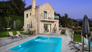 A stone house with a pool, outdoor seating, and a view of the hills. - Villa Piedra (Platanias)