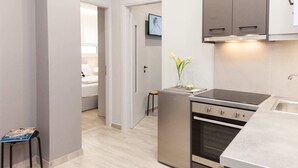 A modern kitchen with a built-in oven, a stove, and a sink. There is a small table with a vase of flowers and a magazine on it.