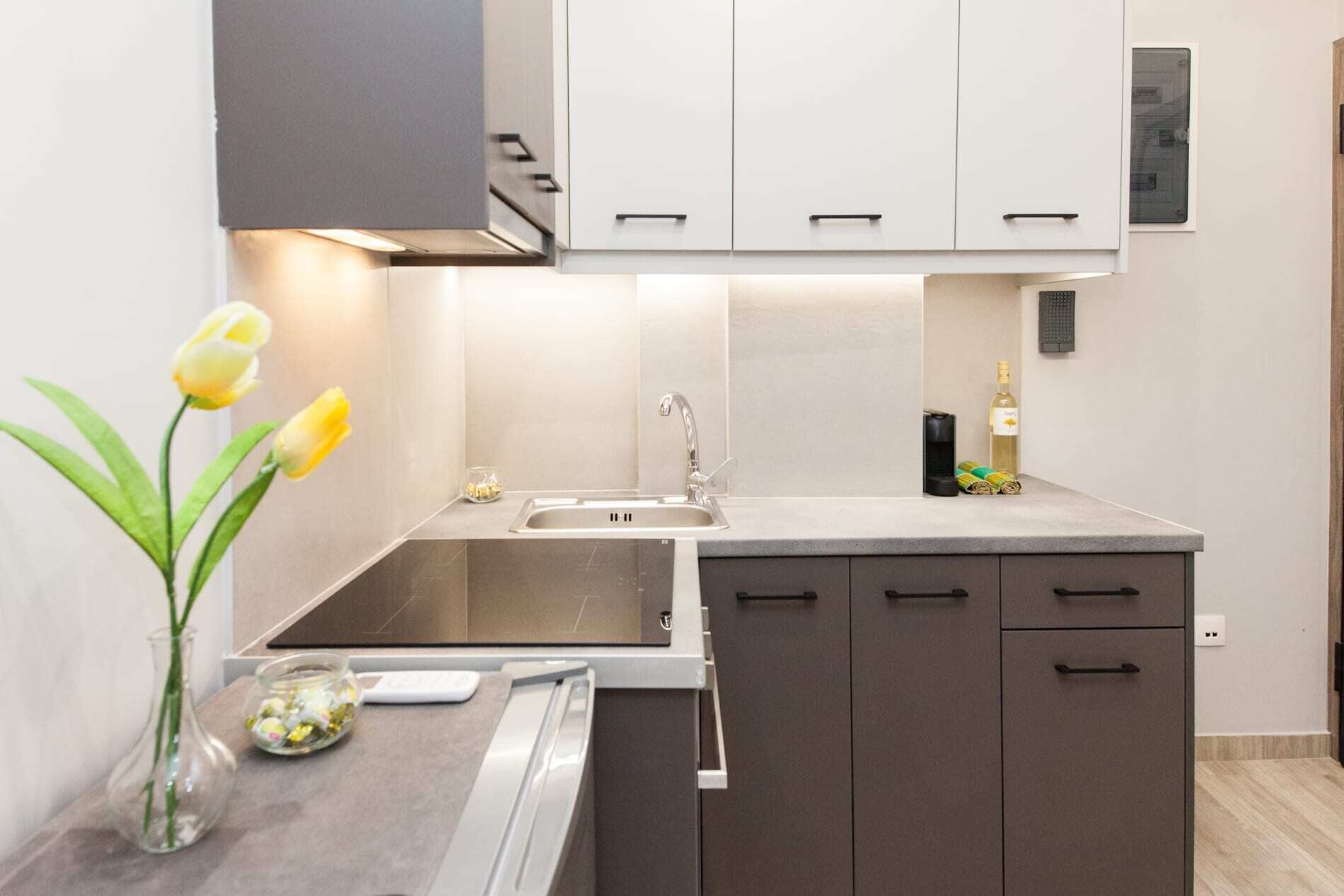 A modern kitchen with a sink, cabinets, and a vase with flowers.