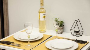 A table set with white plates, two wine glasses, a bottle of white wine, and a small potted plant.