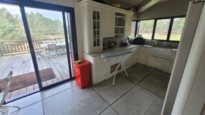 A kitchen with a large sliding glass door leading to an outdoor deck. - Exceptional family lodge in the heart of nature, 60 kms from Paris. (LA BOISSIÈRE-ÉCOLE)