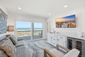 Une cuisine moderne dotée d’une grande fenêtre, un coin repas offrant une vue sur la plage et un espace salon confortable.