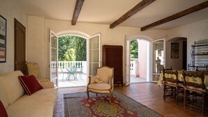 A spacious living room with a large red patterned rug, a white sofa, a chair, and a wooden table with a tablecloth. - Stunning private villa for 11 people with private pool, A/C, WIFI, TV and patio (Draguignan)