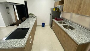 A modern kitchen with granite countertops, wooden cabinets, a built-in microwave, and a stainless steel sink. - Depas VAL704 By Trvl2hm Mazatlan Regency (Mazatlán)