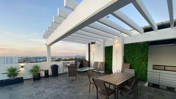 A rooftop patio with a table and chairs, a grill, and a view of the cityscape. - Depas VAL704 By Trvl2hm Mazatlan Regency (Mazatlán)