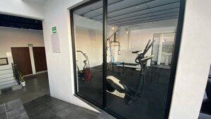A modern gym with exercise equipment, a glass door entrance, and a sign indicating a room number. - Depas VAL704 By Trvl2hm Mazatlan Regency (Mazatlán)