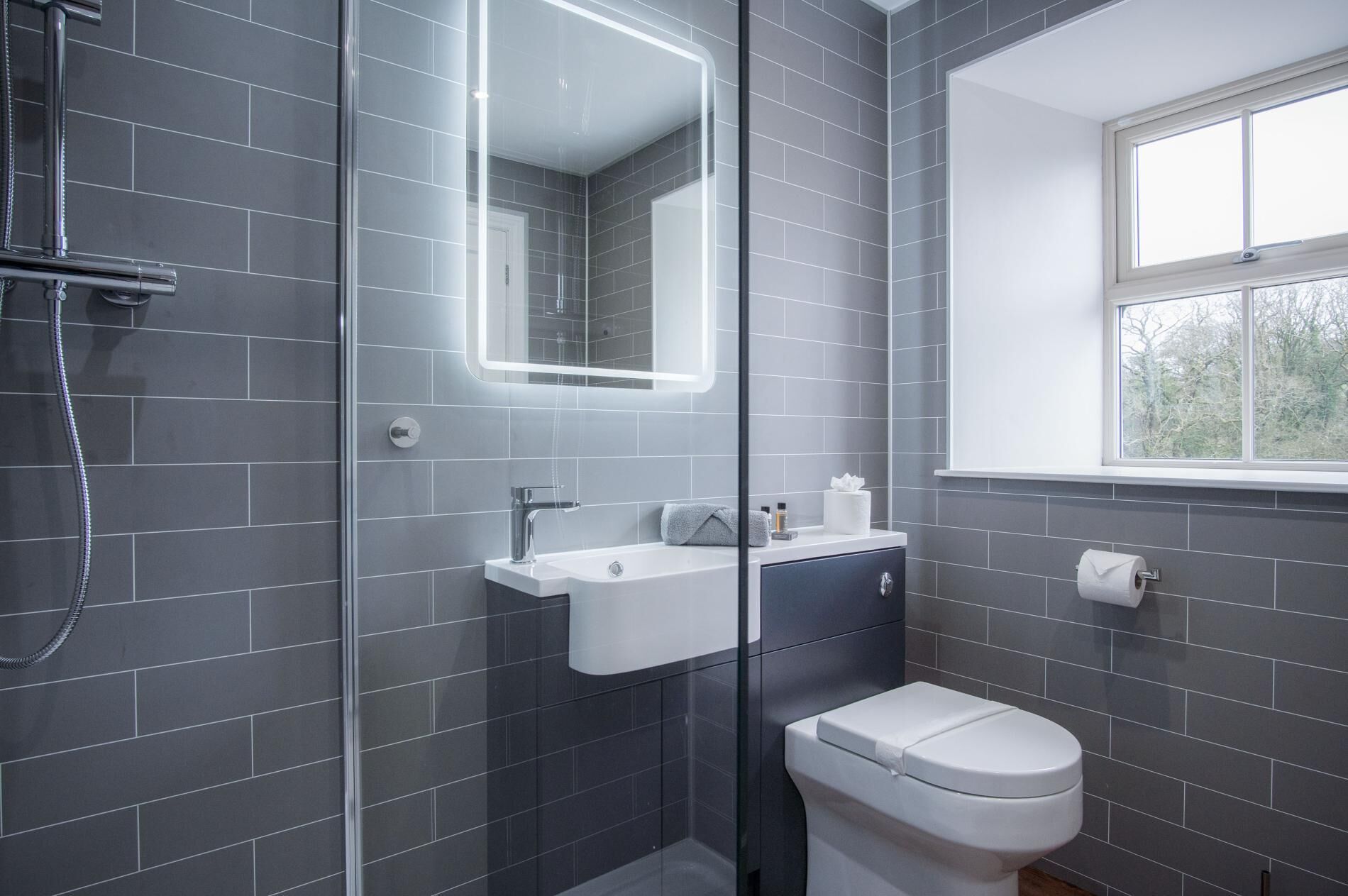 Une salle de bain moderne avec une douche à parois de verre, un lavabo blanc et des toilettes.