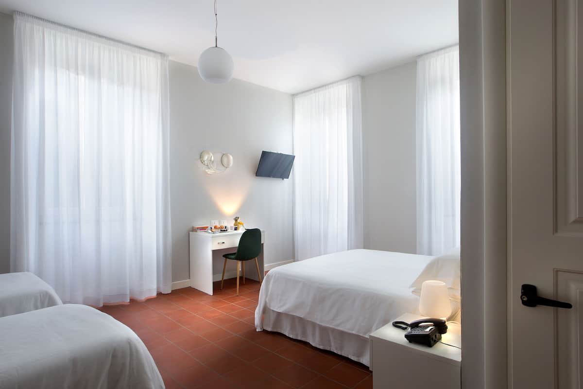 A hotel room with two beds, a desk with a chair, a television, and a telephone.