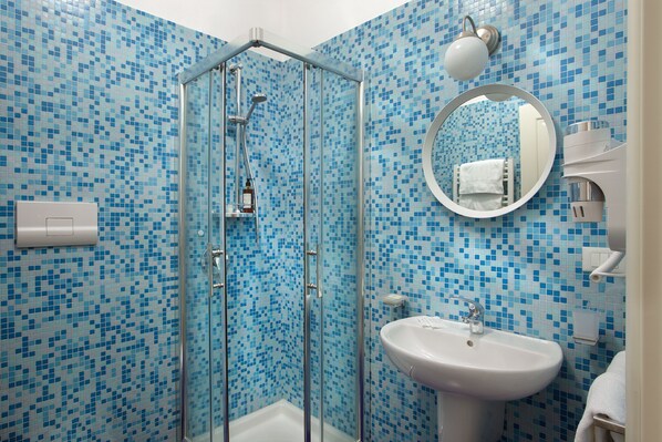 A bathroom with a glass-enclosed shower, a sink, and a mirror.
