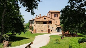 Un edifici de pedra amb un carrer d'accés pavimentat i una petita zona de jardí.