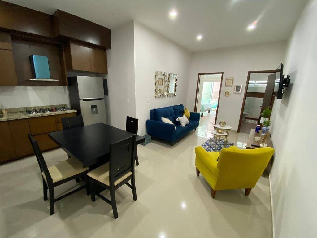 Une cuisine moderne avec un coin repas, un canapé bleu et un fauteuil jaune.