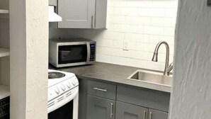 Una cocina compacta con microondas, estufa y armarios grises.