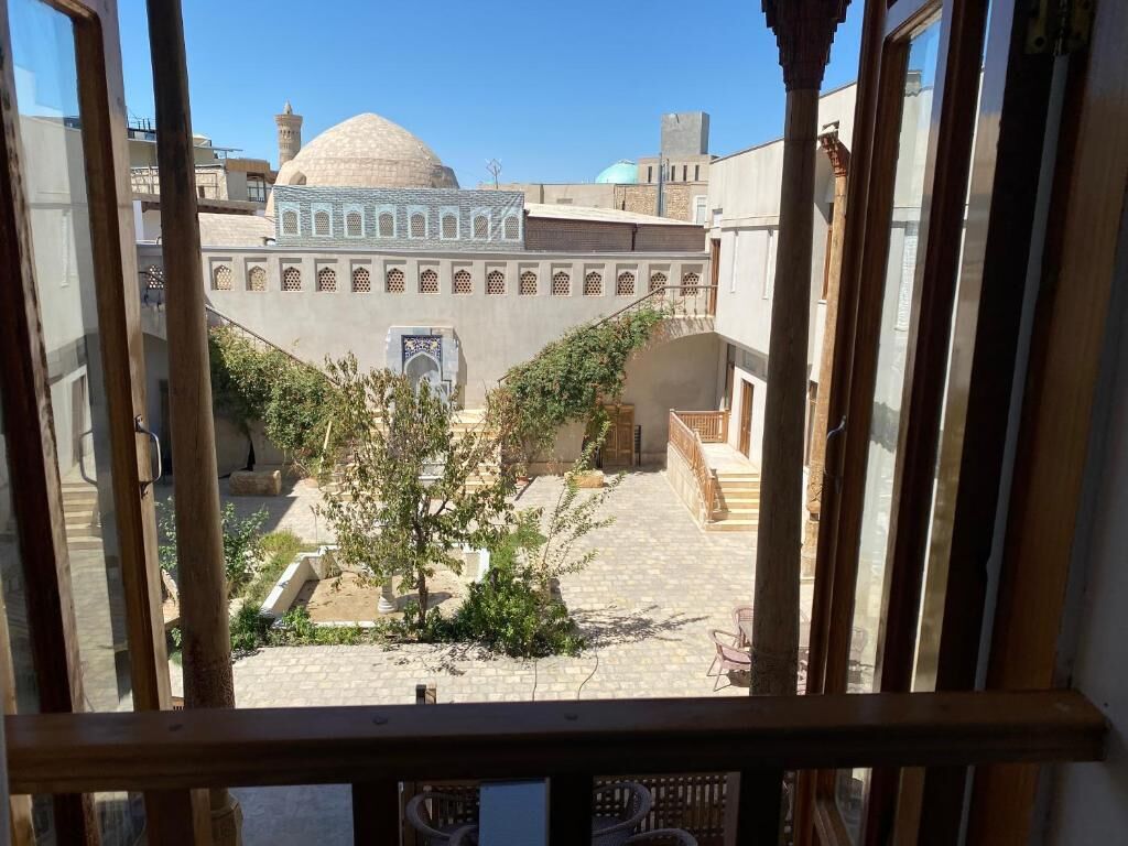 Une cour offrant une vue sur un bâtiment doté d’un dôme et d’arcades.