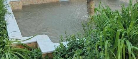 Un patio con una fuente, una escalera y un muro con detalles decorativos.