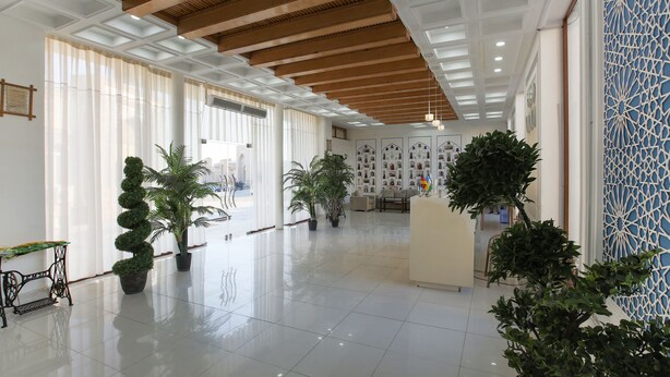 Eine geräumige Lobby mit hoher Decke, großen Fenstern und Kübelpflanzen.