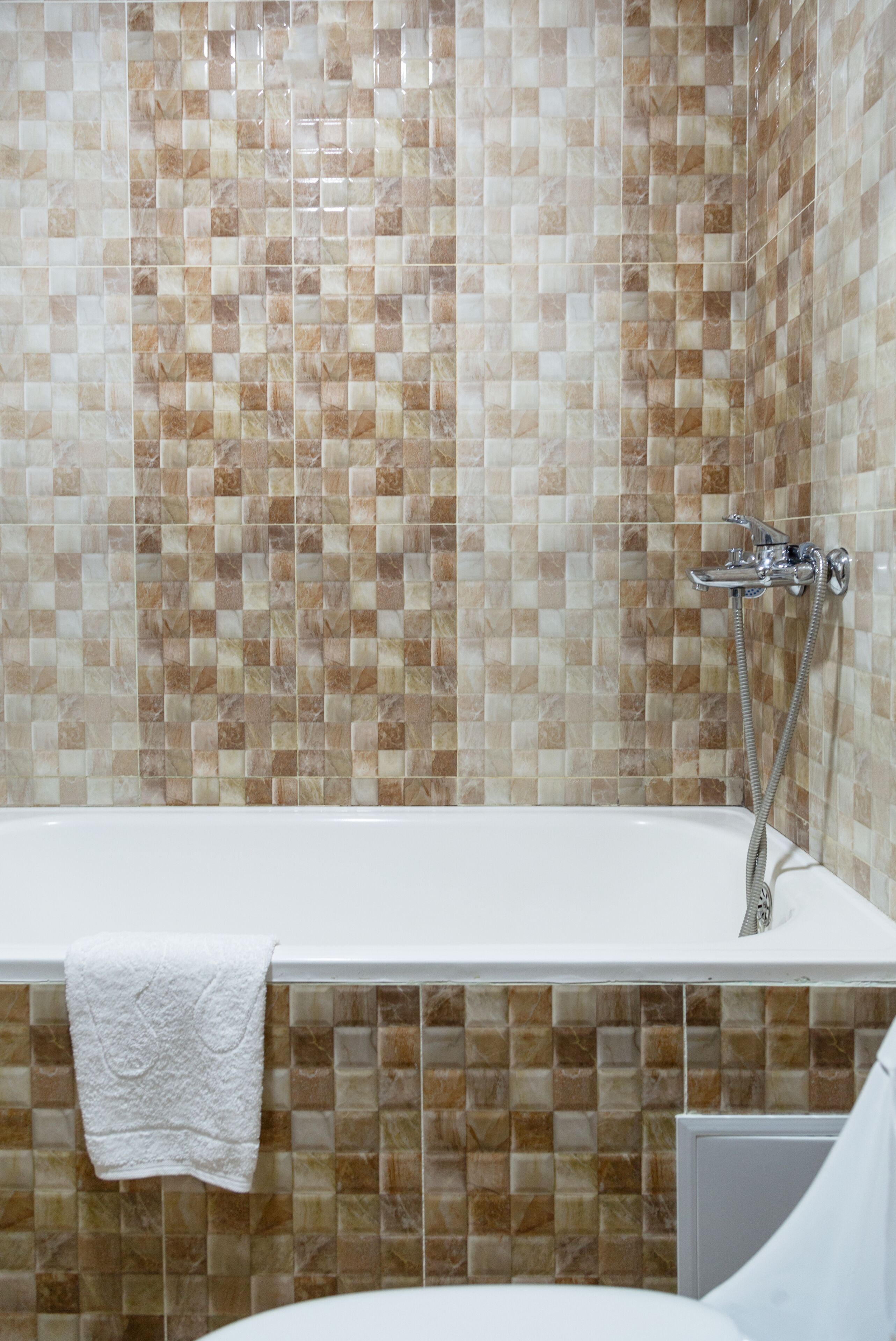 A bathroom with a tiled wall and a bathtub.