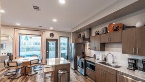 A modern kitchen with a dining area, stainless steel appliances, and a view of the city. - Glam Downtown Retreat w/ Pool | Girls’ Trips & Bachelorettes | Sleeps 8 (Nashville)